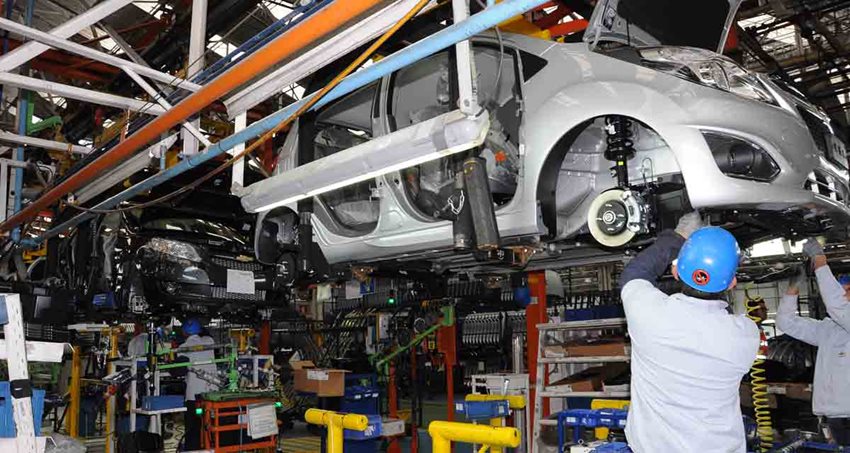 Dos hombres, con equipo de seguridad, haciendo revisión mecánica a un automóvil.