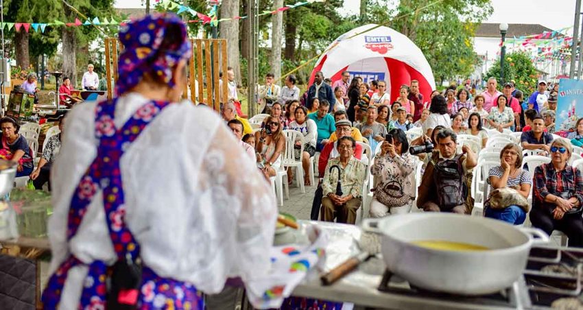 Mujer cocinando desde tarima y personas observándola.
