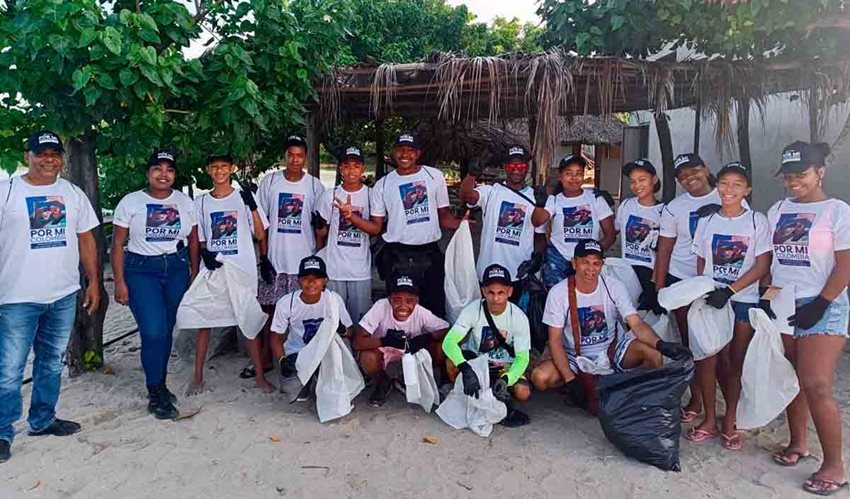 Descripción de la imagen: Hombres y mujeres, con gorras negras y camisetas blancas, posando para la foto cuando recogen basuras.