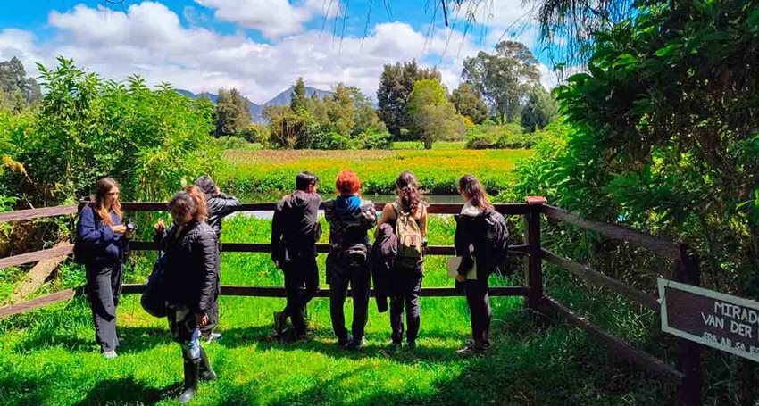 Descripción: Personas observando la naturaleza, recostadas en una cerca.