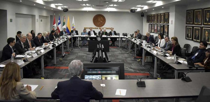 Hombres y mujeres reunidos alrededor de una mesa cuadrada durante Alianza del Pacífico.