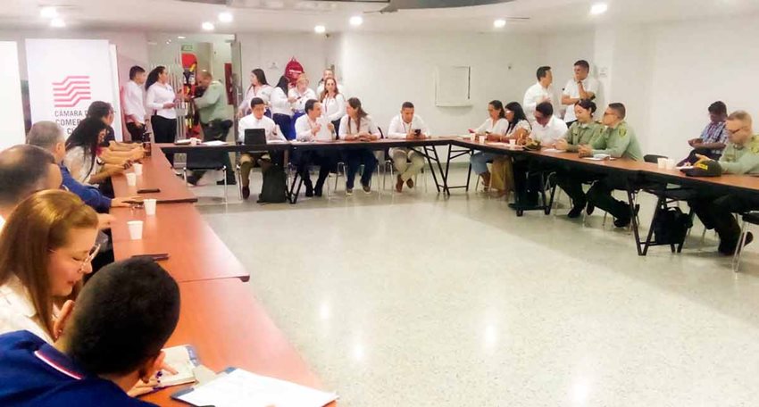 Descripción de la imagen: Hombres y mujeres reunidos en mesa grande, conversando.