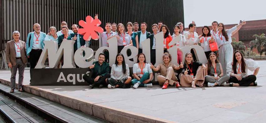 Personas posando para la foto en un letrero grande y blanco que dice Medellín.