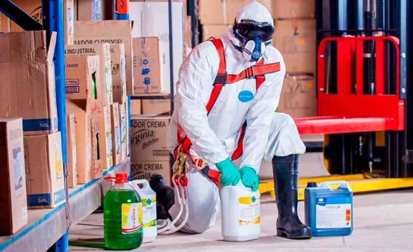 Persona con traje blanco de protección, destapando botellas de químicos.