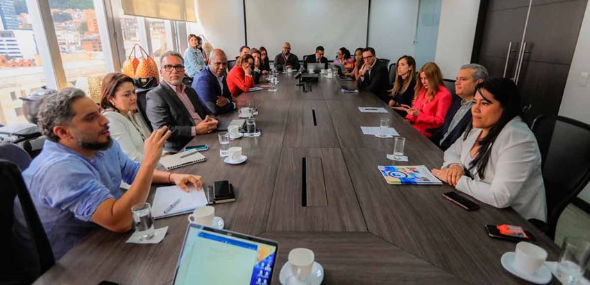 Mujeres y hombres reunidos alrededor de una mesa, dialogando.