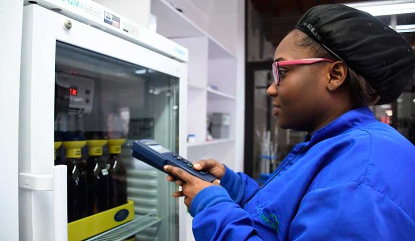 Mujer morena con uniforme trabajando frente a una máquina.