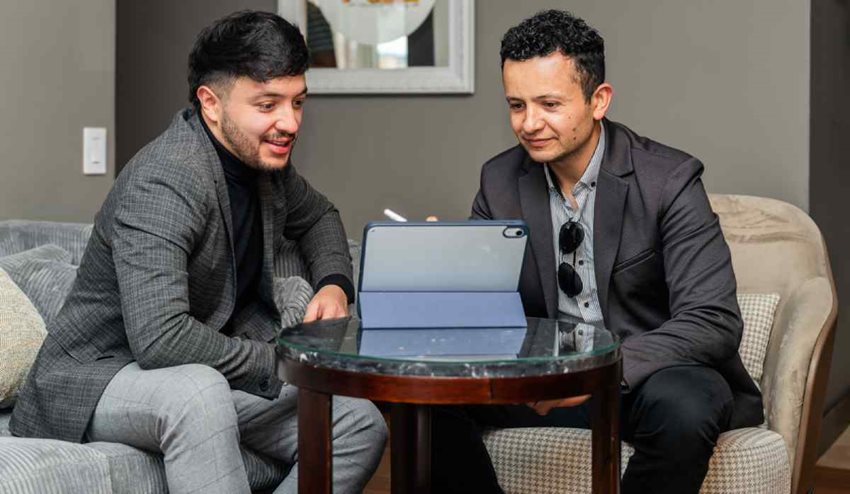 Dos hombres, de traje, frente a computador portátil revisando Circular Única de Calidad Turística.