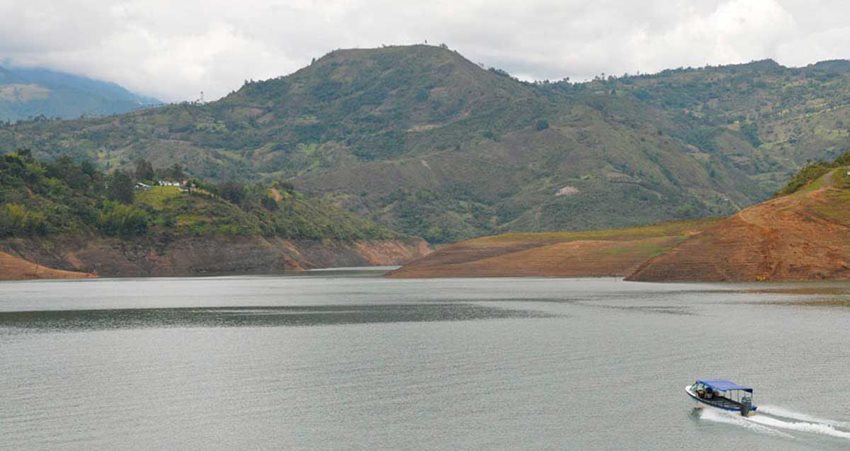 Lancha atravesando lago rodeado de montañas.