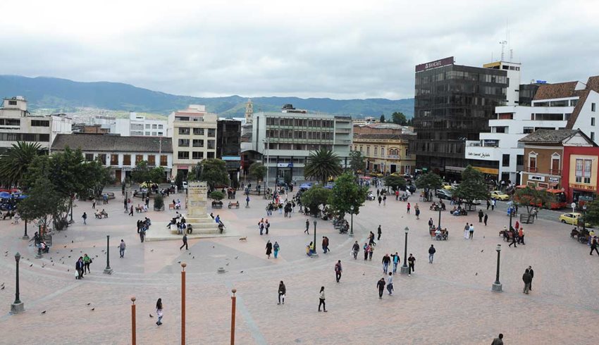 Fotografía de un parque central, con personas caminando y edificios alrededor.