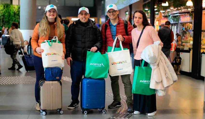 Descripción de la imagen: Dos hombres y dos mujeres posando para la foto con maletas, chaquetas y gorras.