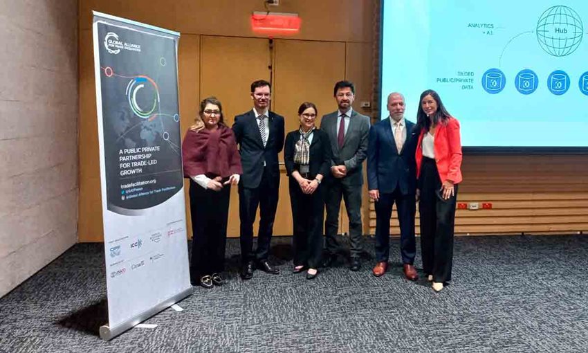 Tres mujeres y tres hombres, vestidos formalmente, posando para la foto al lado del escenario.