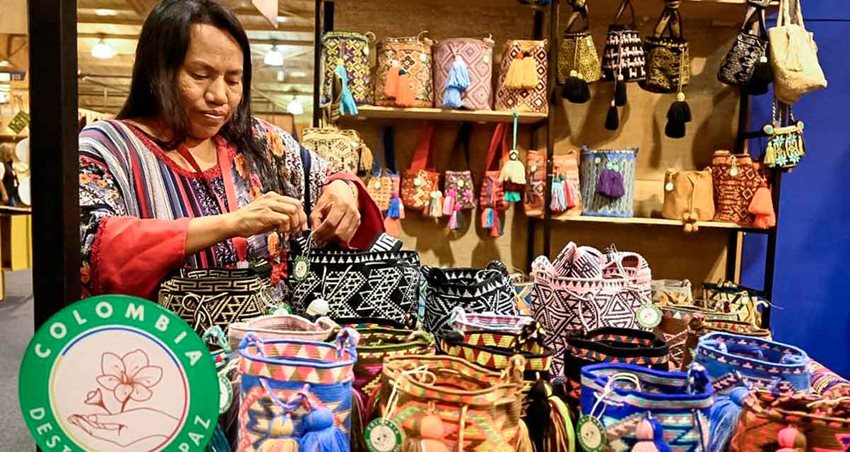 Mujer indígena exhibiendo sus mochilas.