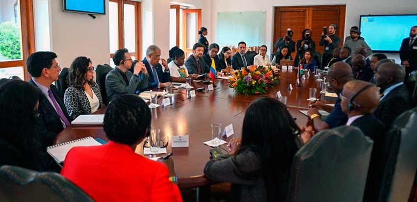 Hombres y mujeres de los gobiernos de Kenia y Colombia sentados en una mesa ovalada, dialogando.