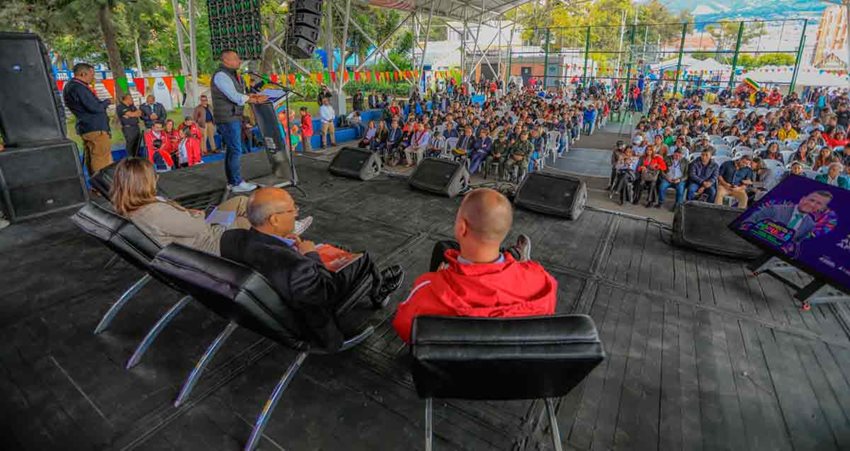 Fotografía general, desde el escenario, de los panelistas y el público asistente sentado en sillas.