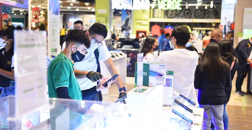 Personas viendo celulares en sección de tecnología de almacén de cadena.