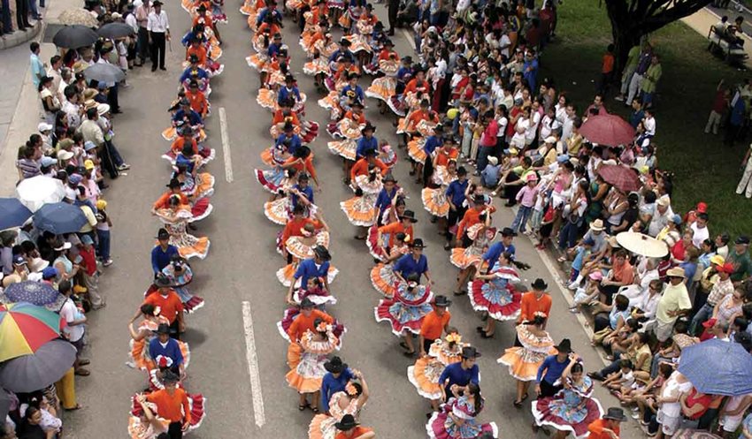 Hombres y mujeres con traje del joropo bailando en medio de la calle.