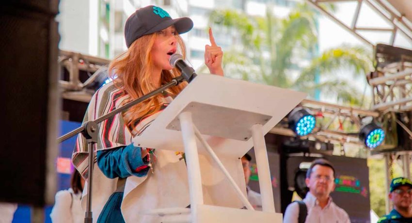 Descripción: Ministra Diana Morales hablando por micrófono, en atril, desde el escenario.