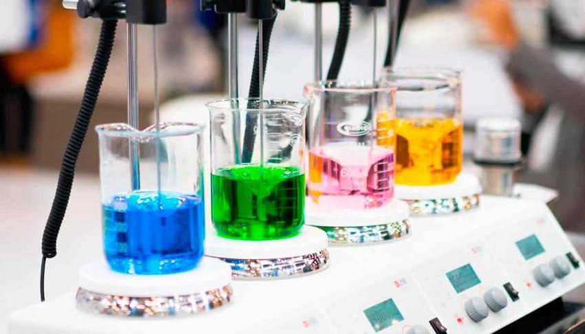 Cuatro recipientes con líquidos de colores, listos para analizar en laboratorio.