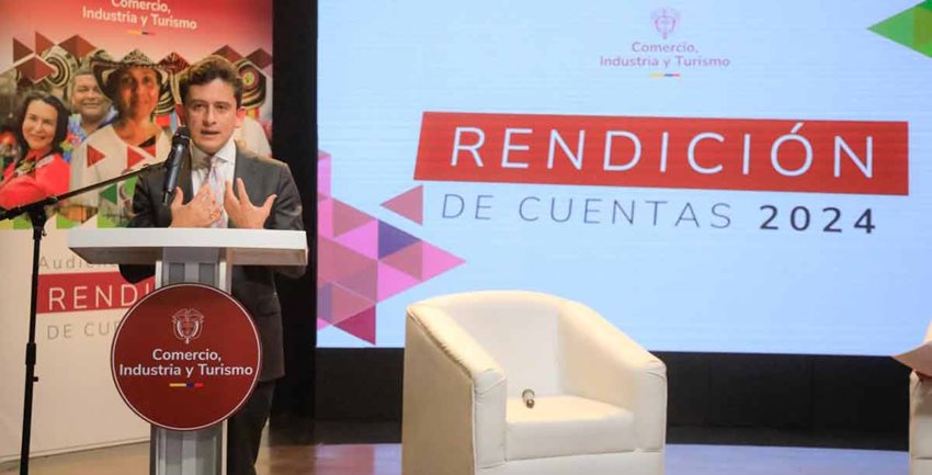 Ministro Luis Carlos Reyes, de pie en el atril, hablando por micrófono a la cámara.