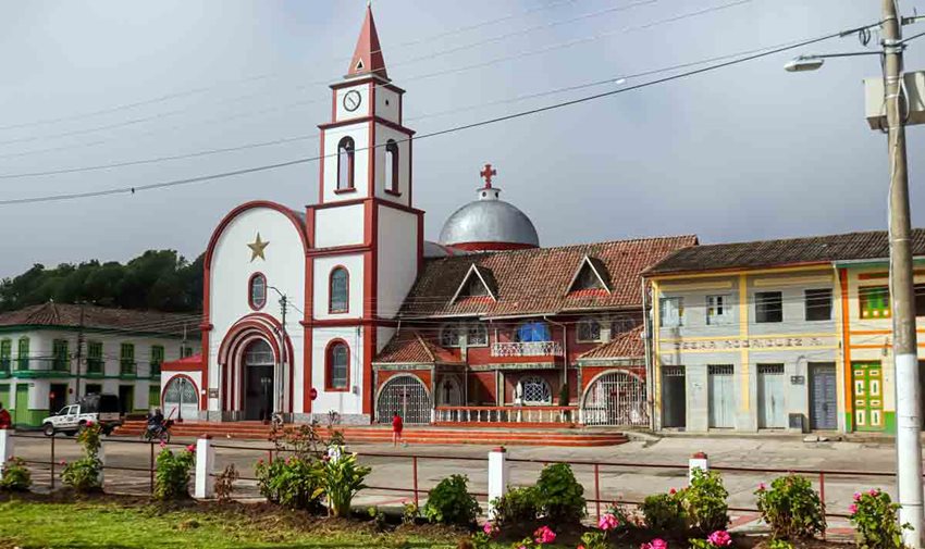 Descripción: Foto, de día, de la iglesia de Murillo, en Tolima, con casas y el parque alrededor.