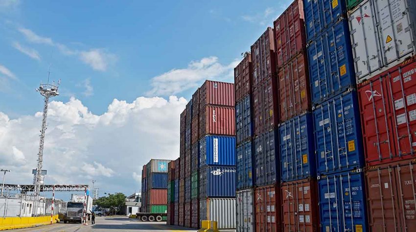Contenedores de colores descargados en medio de la calle de un puerto y un camión entrando.
