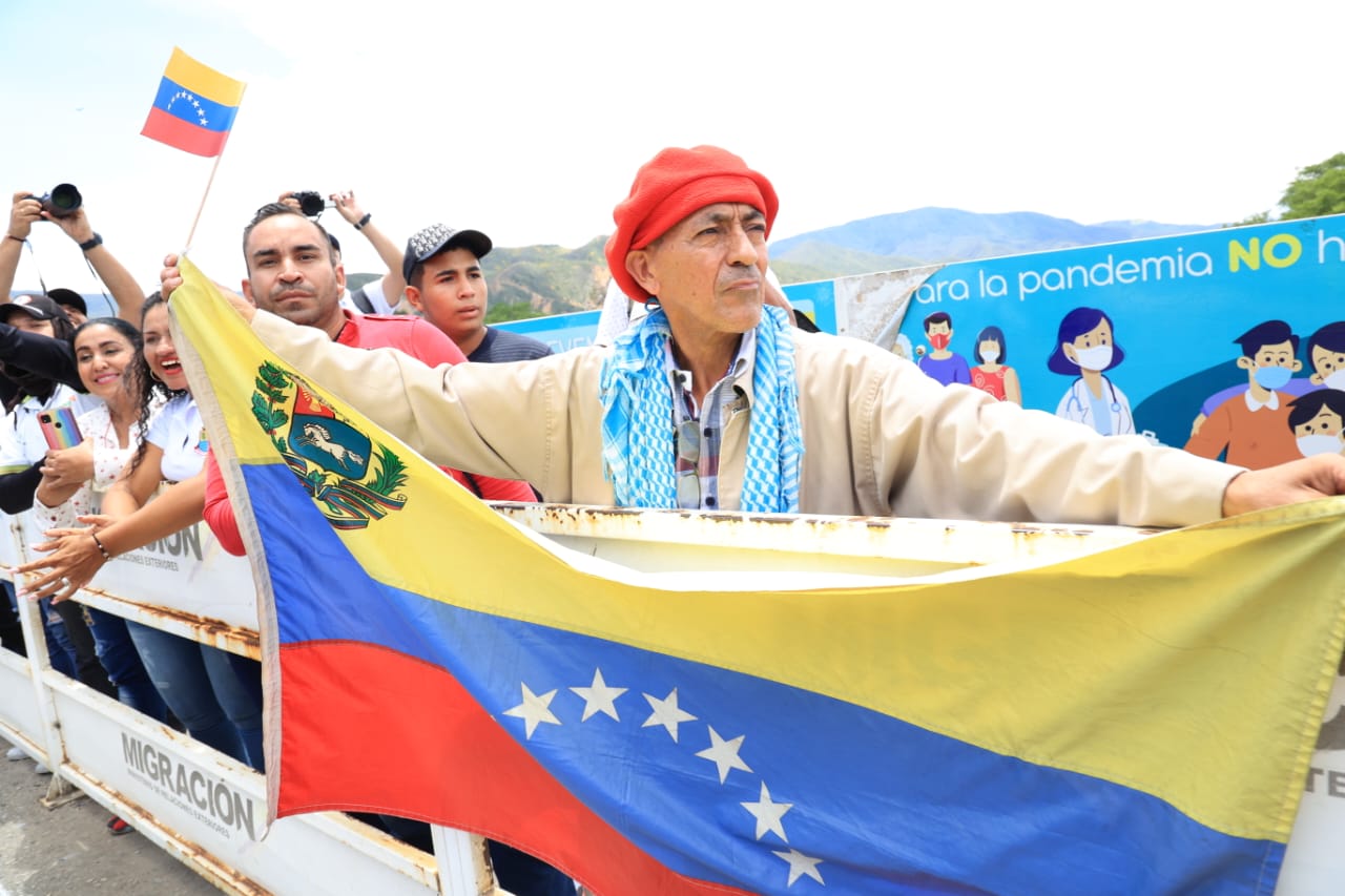 Persona, con gorro rojo, sosteniendo una bandera de Venezuela.