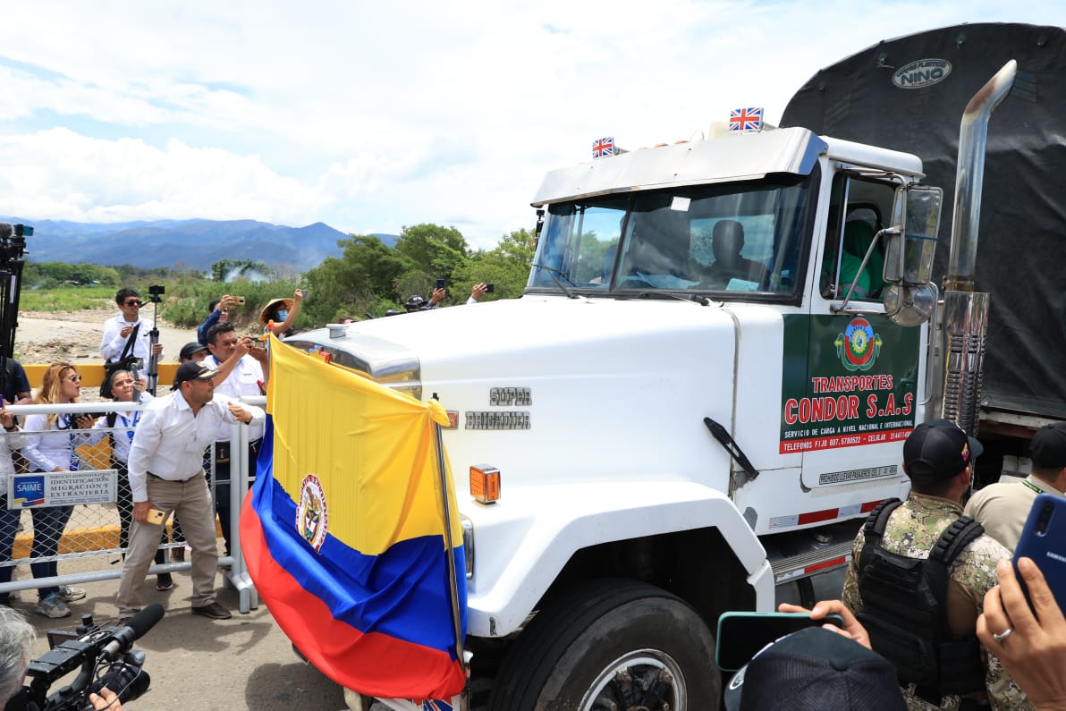 Camión blanco, con bandera de Colombia, transitando por el puente.